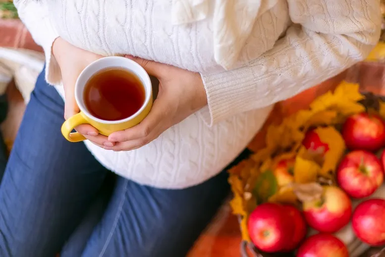 kobieta w ciąży pijąca trzymająca kubek herbaty